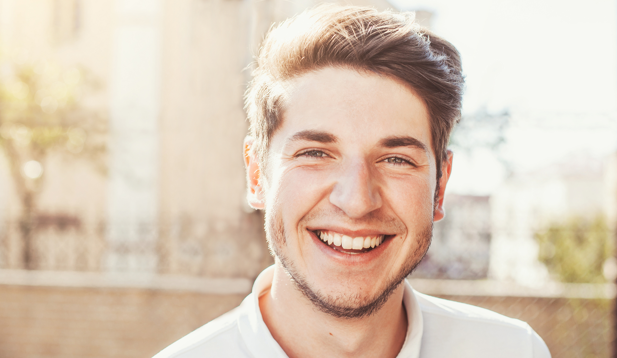 Man smiling in the sun with all-ceramic dental restorations