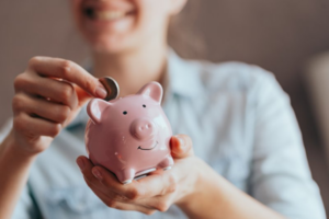 Woman smiling as she puts a coin into her piggy bank